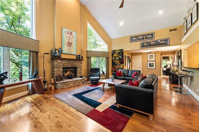 living room featuring a fireplace, high vaulted ceiling, and light hardwood / wood-style floors