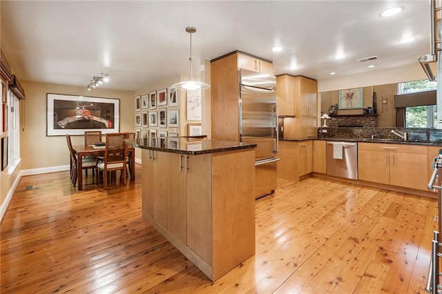 kitchen with kitchen peninsula, appliances with stainless steel finishes, light wood-type flooring, a breakfast bar, and decorative light fixtures