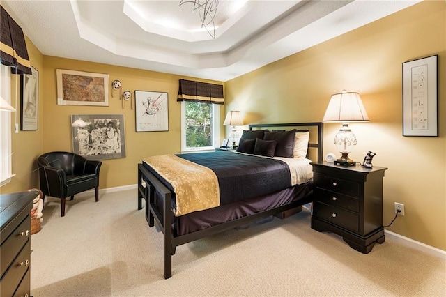 bedroom with a raised ceiling and light colored carpet