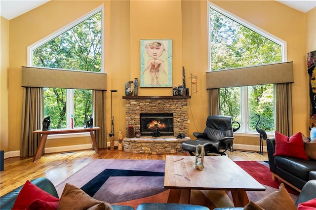 living room featuring a stone fireplace, plenty of natural light, high vaulted ceiling, and hardwood / wood-style flooring