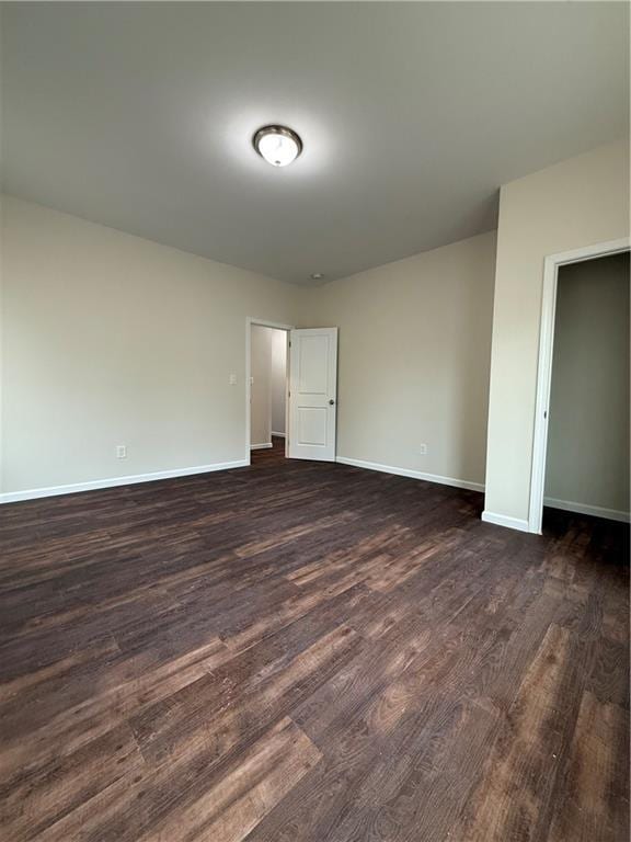 empty room with dark wood-type flooring and baseboards