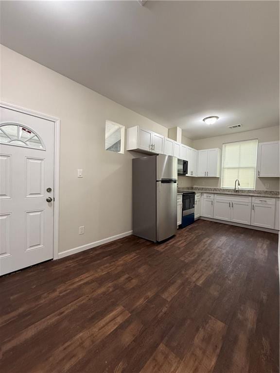 kitchen with white cabinets, dark wood-style flooring, baseboards, visible vents, and black appliances