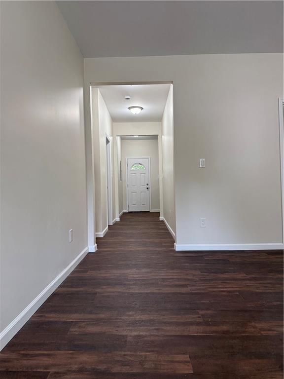 hall featuring baseboards and dark wood-style floors
