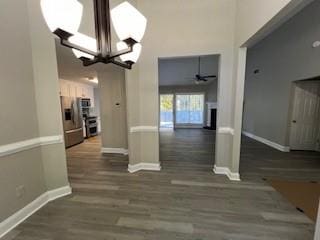 unfurnished dining area with dark hardwood / wood-style flooring and ceiling fan with notable chandelier