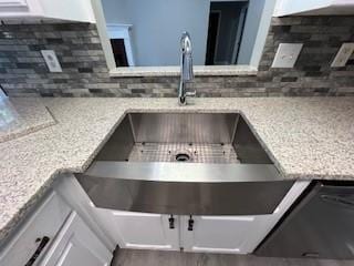 details featuring decorative backsplash, light stone counters, and white cabinetry