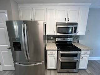 kitchen with light hardwood / wood-style floors, white cabinetry, and stainless steel appliances