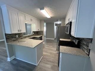 kitchen featuring kitchen peninsula, stove, light hardwood / wood-style floors, a textured ceiling, and white cabinets