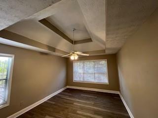 unfurnished room featuring a tray ceiling, ceiling fan, and dark hardwood / wood-style floors