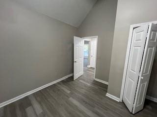 unfurnished bedroom with dark hardwood / wood-style flooring, high vaulted ceiling, and a closet