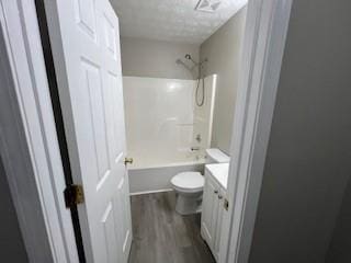 full bathroom with shower / bath combination, vanity, a textured ceiling, hardwood / wood-style floors, and toilet