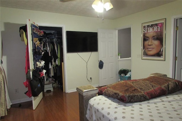 bedroom featuring a spacious closet, dark hardwood / wood-style floors, ceiling fan, and a closet