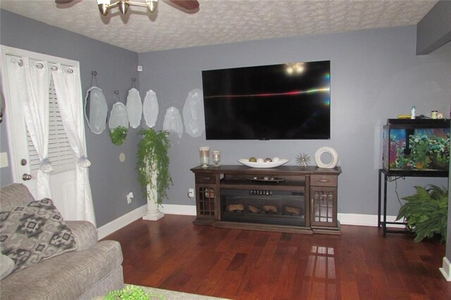 living room featuring ceiling fan, a textured ceiling, and dark hardwood / wood-style flooring