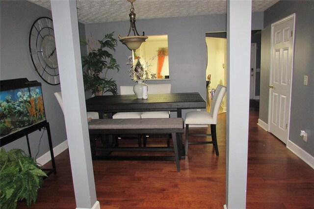 dining space with dark wood-type flooring and a textured ceiling