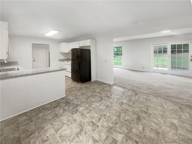 kitchen featuring light stone counters, sink, white cabinetry, light colored carpet, and black refrigerator