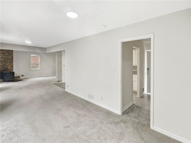 unfurnished living room with light carpet and a fireplace