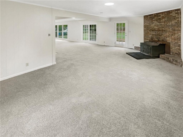 unfurnished living room featuring plenty of natural light, carpet flooring, and a wood stove