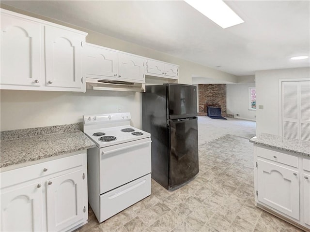 kitchen with black fridge, white electric range oven, white cabinets, light stone countertops, and a fireplace