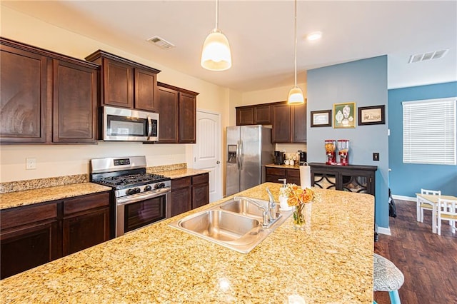 305 Thimbleberry Dr, Dawsonville, GA 30534 - kitchen featuring appliances with stainless steel finishes, dark brown cabinets, dark wood finished floors, decorative light fixtures, and light stone counters