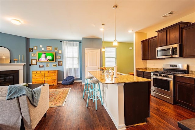 305 Thimbleberry Dr, Dawsonville, GA 30534 - kitchen with appliances with stainless steel finishes, light stone countertops, dark brown cabinets, dark wood finished floors, and a kitchen island with sink