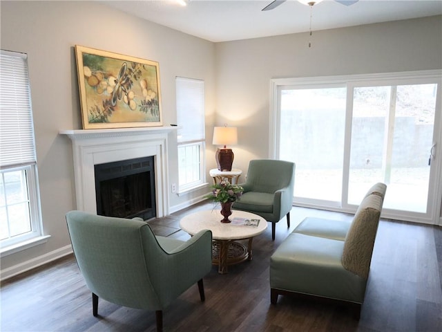 living room featuring ceiling fan, baseboards, wood finished floors, and a fireplace