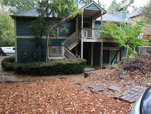 back of property with stairway and a chimney