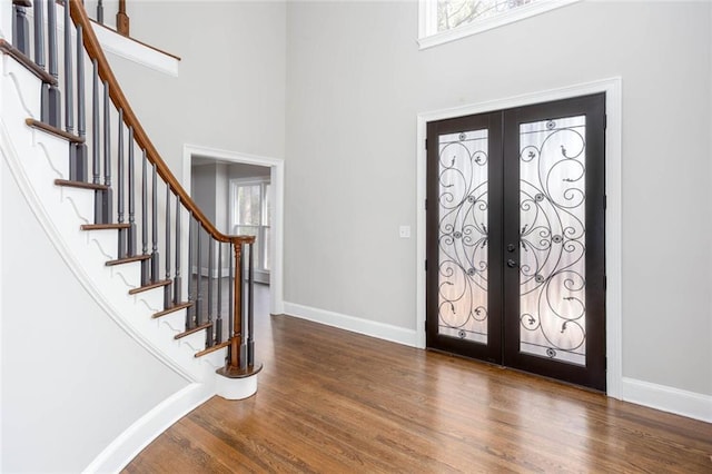 entrance foyer featuring stairway, baseboards, wood finished floors, and french doors