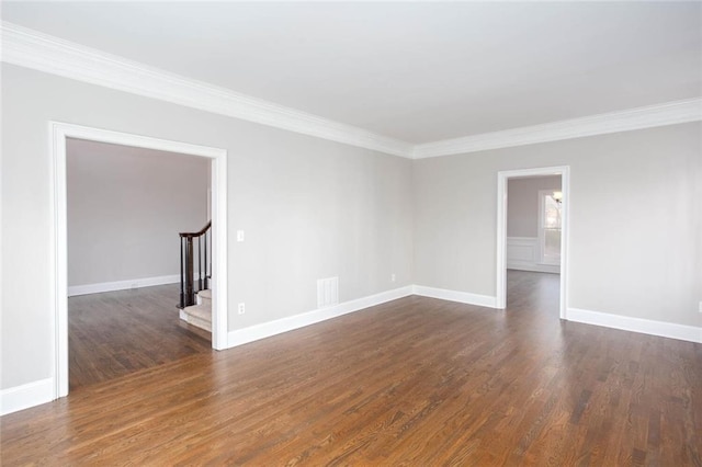 empty room featuring stairs, visible vents, dark wood finished floors, and ornamental molding