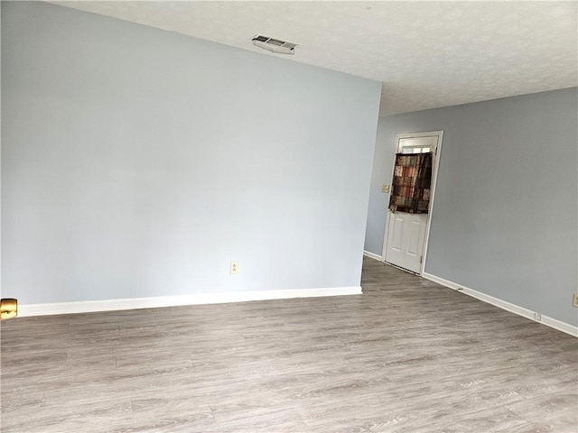 empty room with hardwood / wood-style floors and a textured ceiling