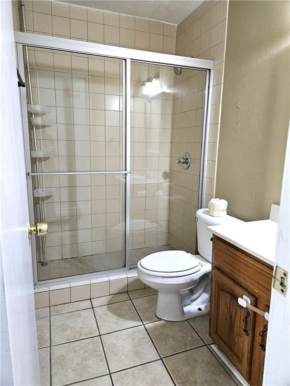 bathroom with vanity, a shower with shower door, tile patterned flooring, and toilet