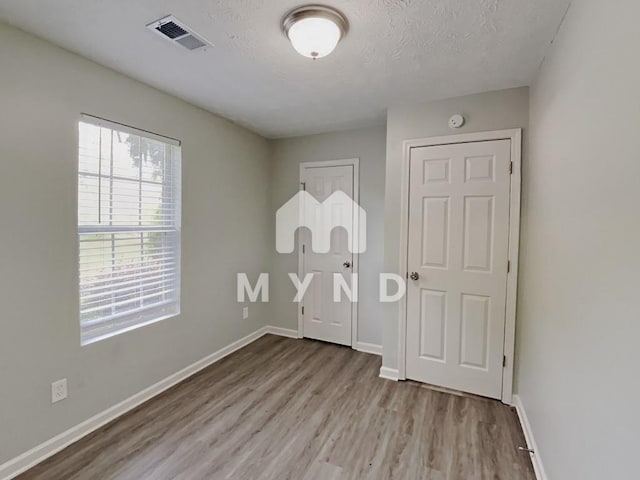 unfurnished bedroom featuring baseboards, visible vents, and wood finished floors