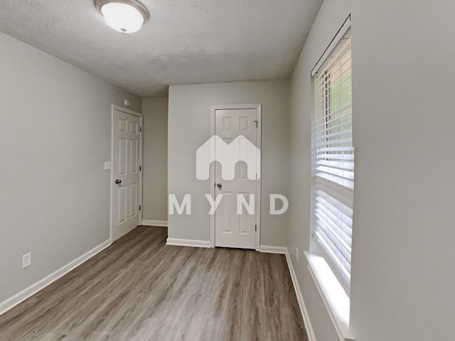 entrance foyer with baseboards, a textured ceiling, and wood finished floors