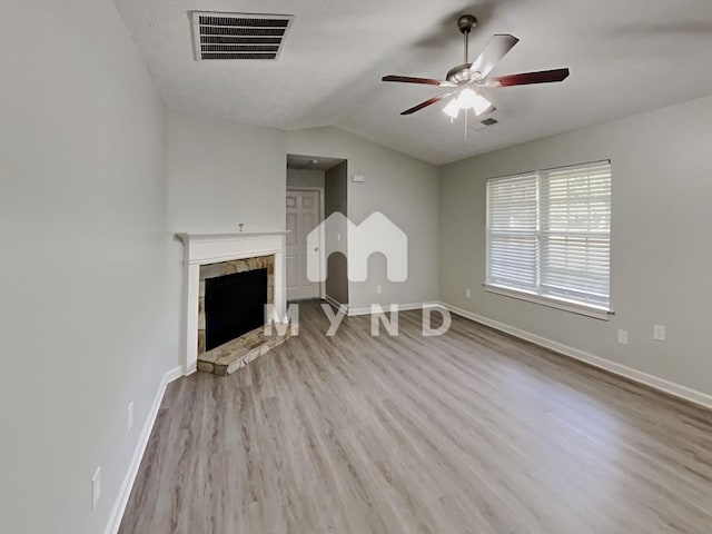 unfurnished living room with wood finished floors, visible vents, vaulted ceiling, a ceiling fan, and a tiled fireplace