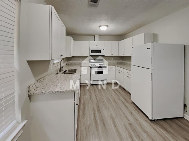 kitchen featuring a sink, white appliances, light stone counters, light wood-type flooring, and visible vents