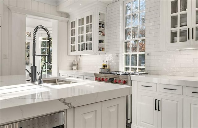 interior space featuring a wealth of natural light, light stone counters, decorative backsplash, and white cabinetry