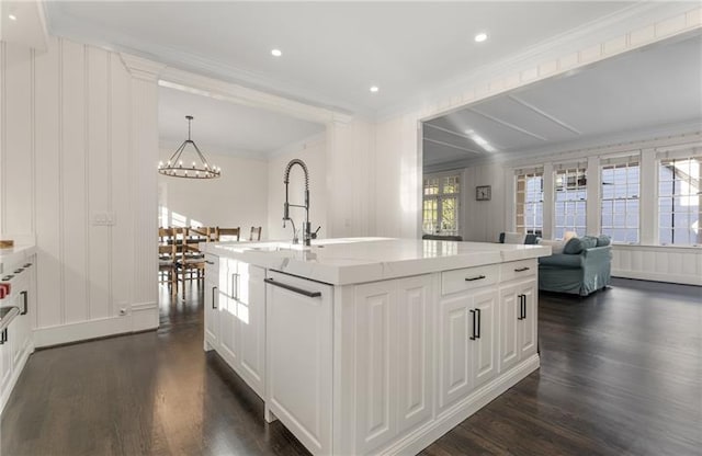 kitchen with a chandelier, an island with sink, white cabinets, dark hardwood / wood-style flooring, and hanging light fixtures