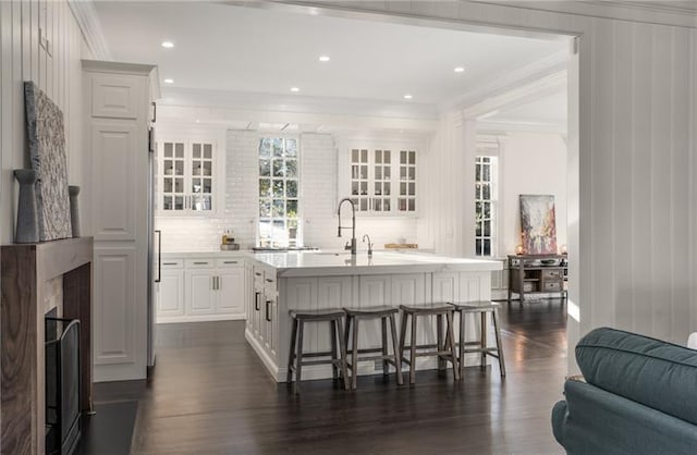 kitchen featuring dark hardwood / wood-style flooring, decorative backsplash, an island with sink, and a breakfast bar