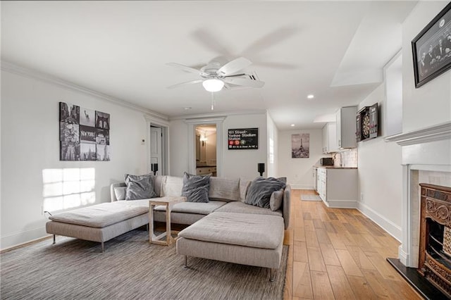 living room with ceiling fan, light wood-type flooring, and ornamental molding