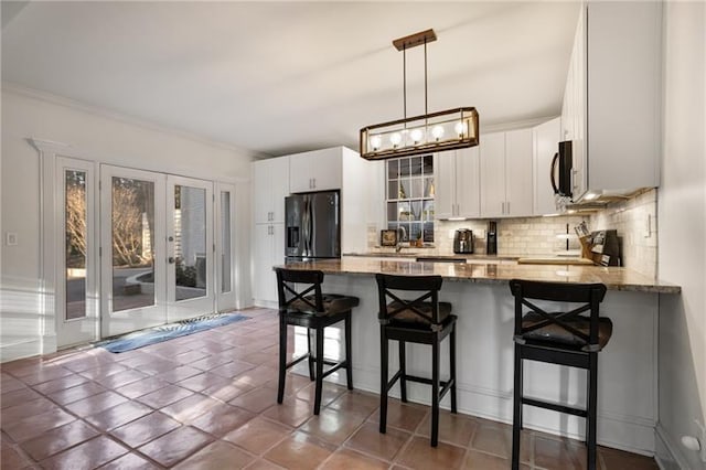 kitchen with kitchen peninsula, stainless steel appliances, white cabinets, and dark stone countertops