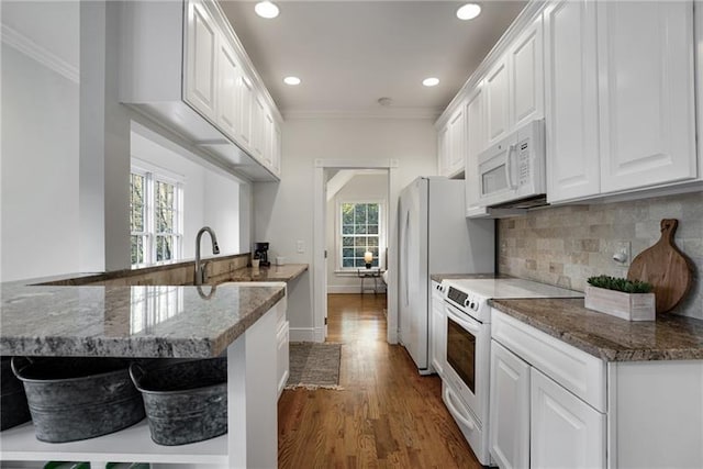 kitchen with crown molding, white cabinets, wood-type flooring, kitchen peninsula, and white appliances