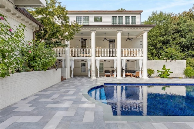 rear view of house with ceiling fan, a patio, a fenced in pool, and a balcony