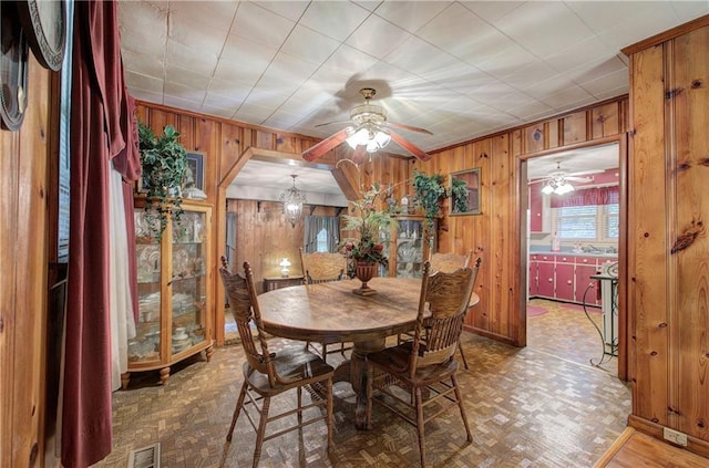 dining area featuring wood walls and parquet flooring