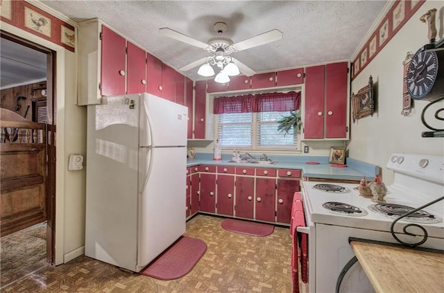 kitchen featuring a textured ceiling, white appliances, red cabinetry, and a sink