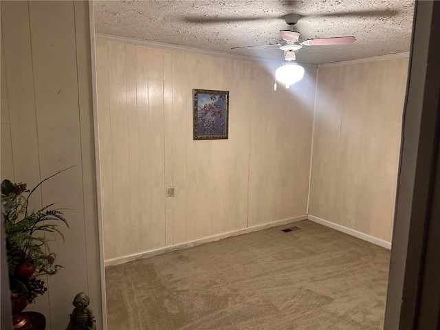 carpeted spare room with crown molding, a ceiling fan, visible vents, and a textured ceiling