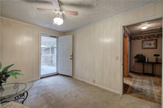 carpeted entryway featuring ceiling fan, a textured ceiling, and wooden walls