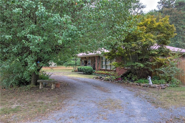 view of front of home featuring brick siding and dirt driveway