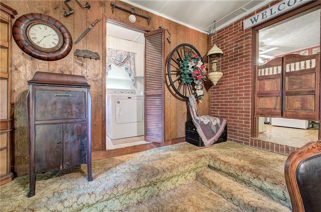 foyer entrance with wooden walls, independent washer and dryer, ornamental molding, and brick wall