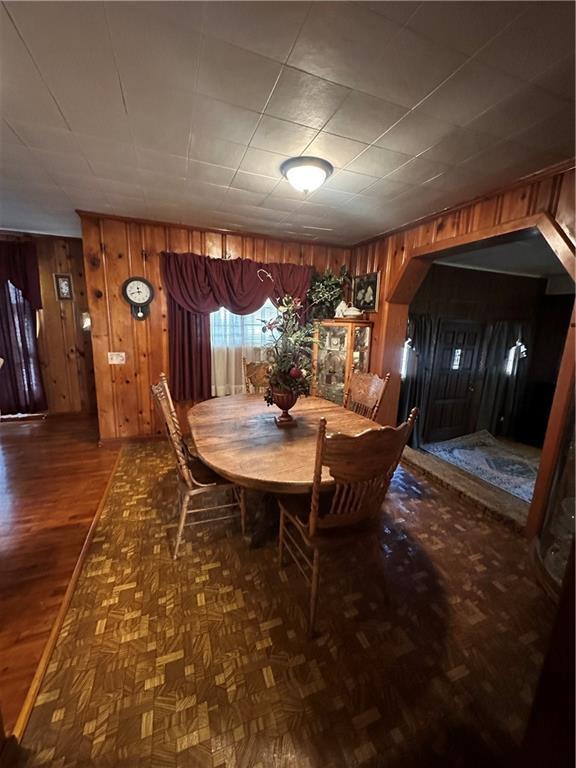 dining room featuring wooden walls and parquet flooring