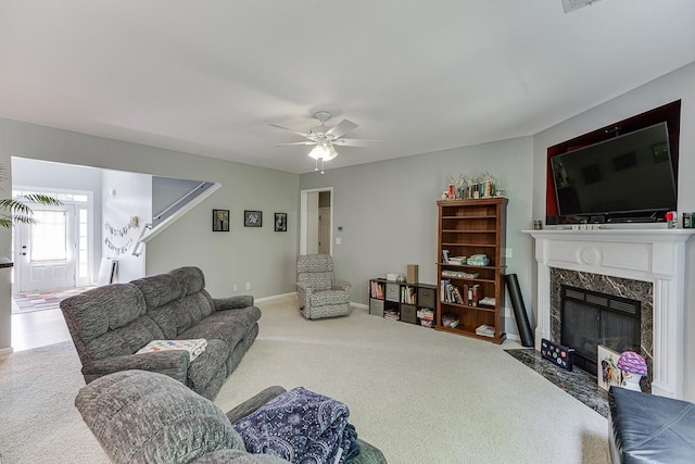 living room with carpet, a high end fireplace, ceiling fan, and baseboards