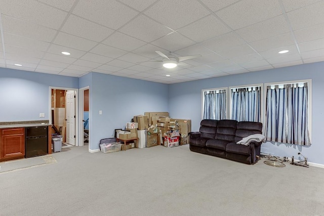 living area featuring carpet, ceiling fan, baseboards, a drop ceiling, and recessed lighting