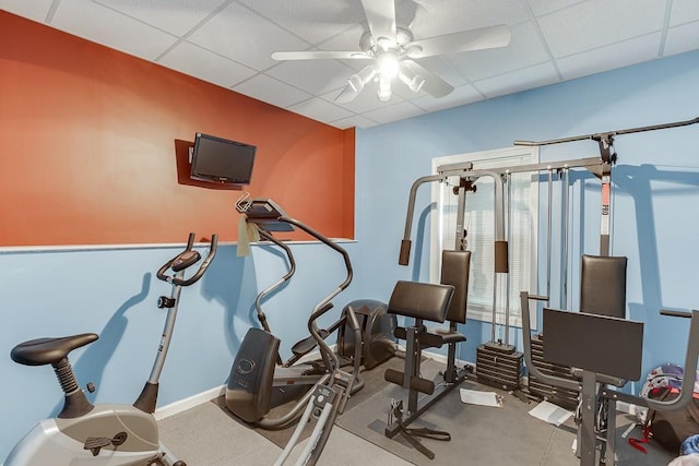 workout room with a drop ceiling, a ceiling fan, and baseboards